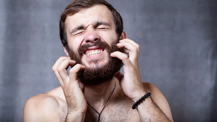 Man scratching his beard due to dryness
